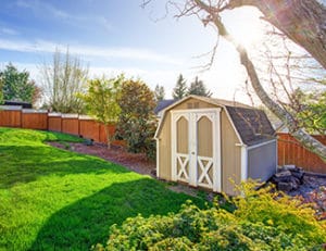 tan shed in front of a brown fence in a backyard