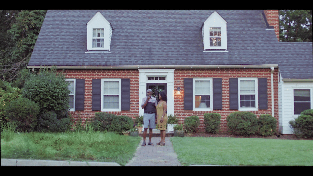 a couple standing in front of their house and lawn
